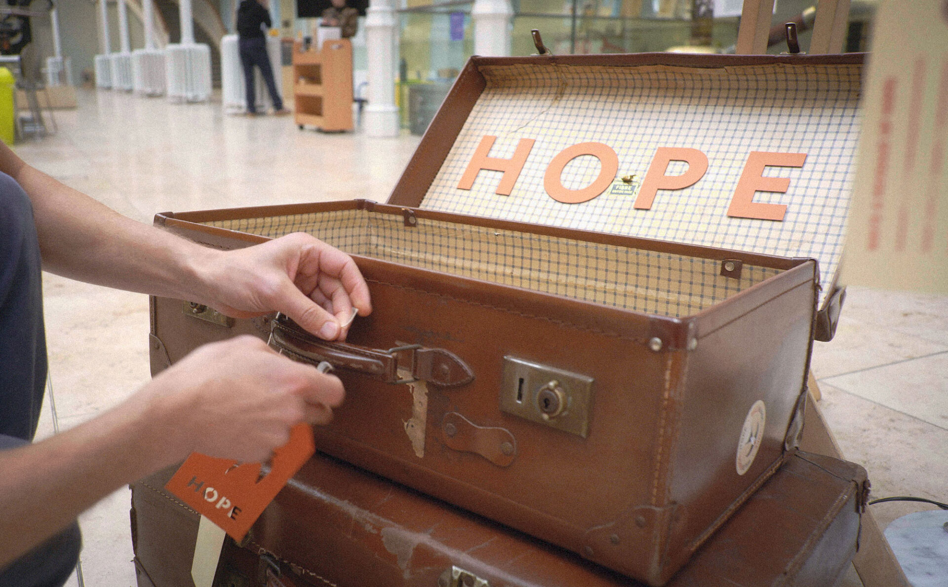 Artist Ed Harrison ties a luggage label to a vintage leather suitcase.