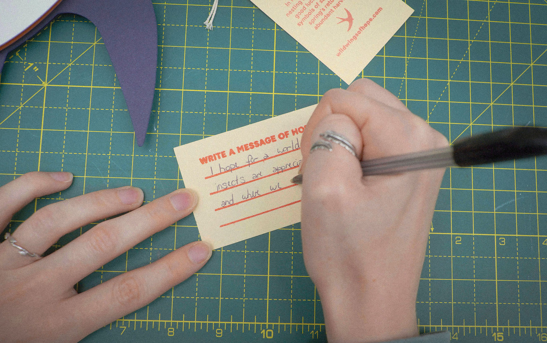 Close-up of a hand writing a message of hope on a luggage label.