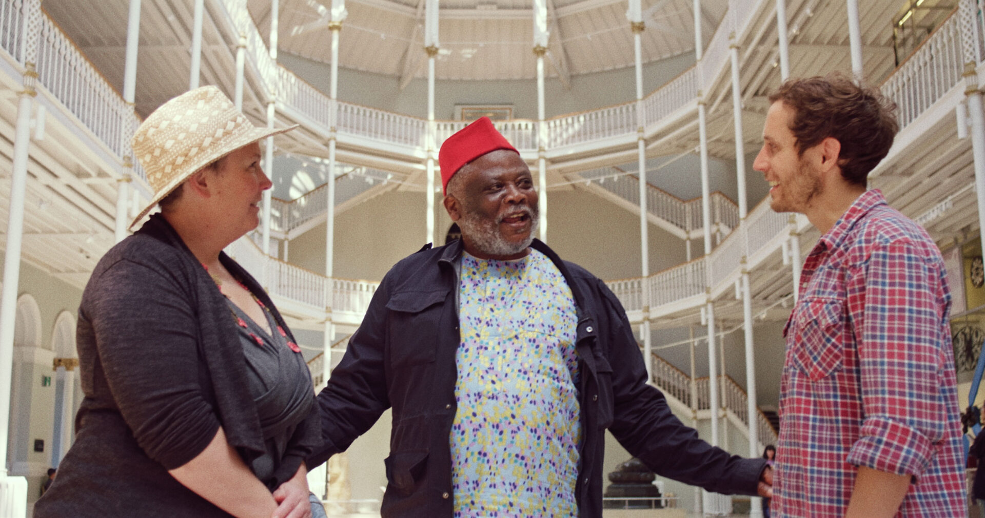 Two storytellers talking with an artist inside a museum gallery during a planning discussion.