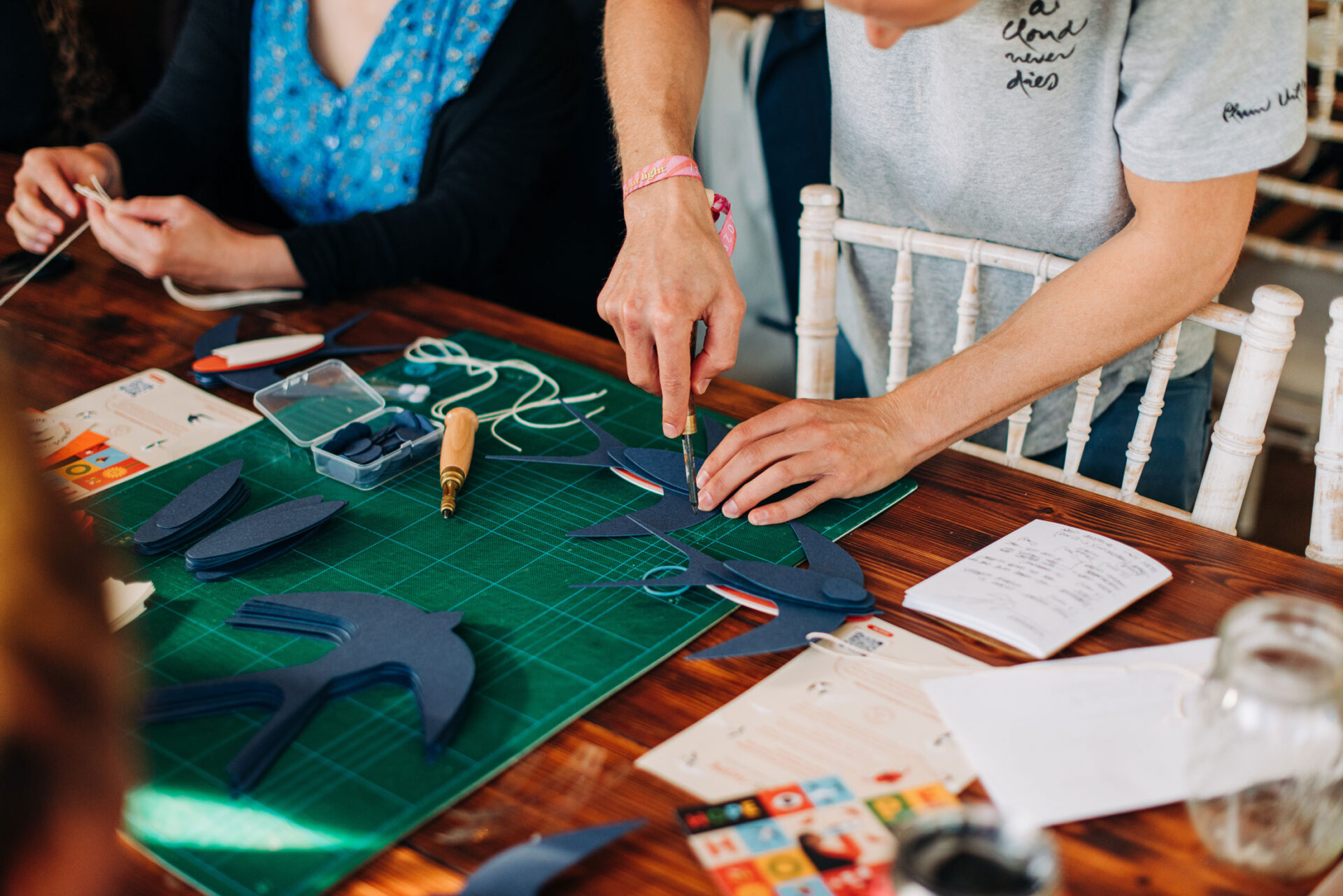 Ed Harrison punching holes in paper facilitating a community craft workshop