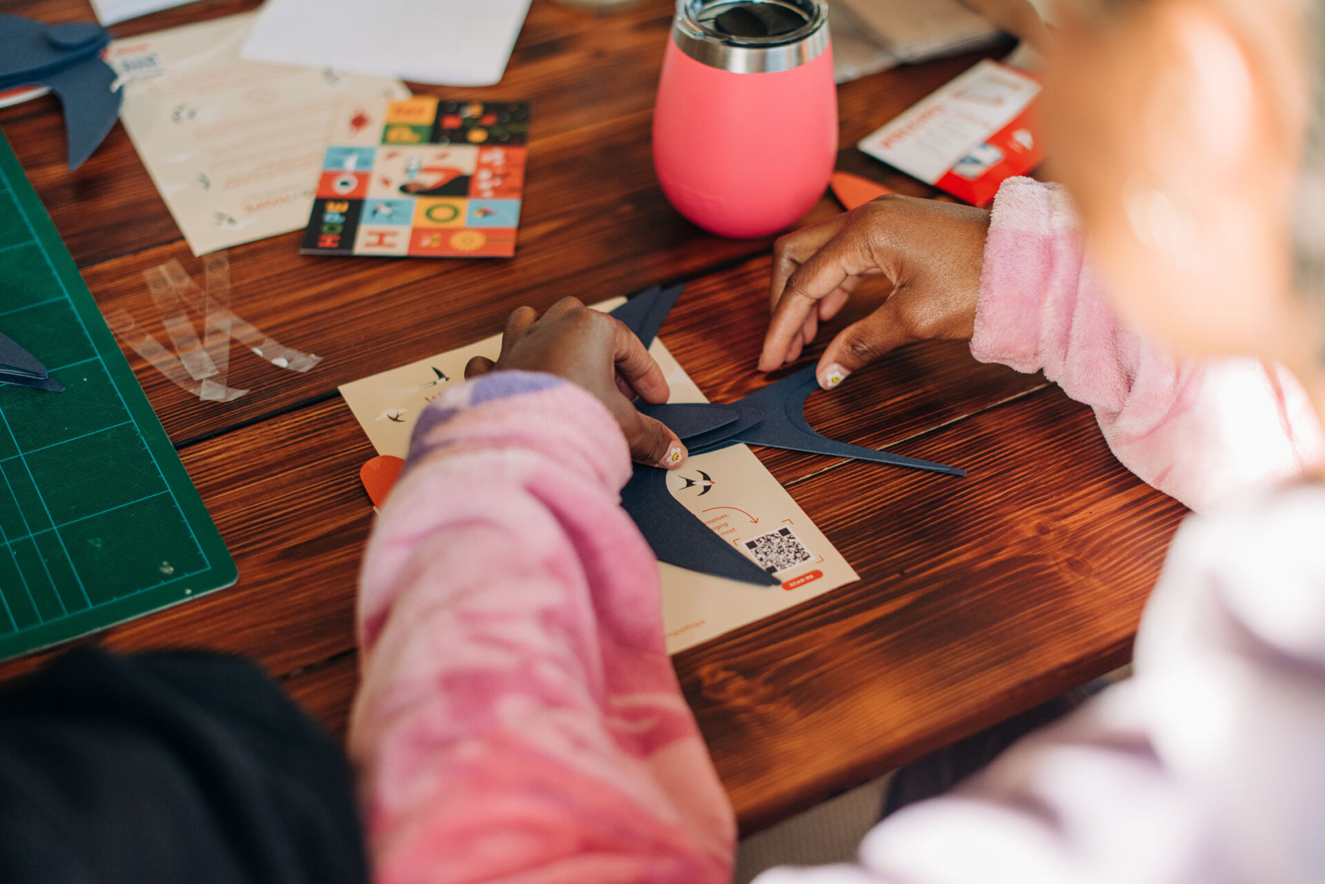 A womans hands as she makes a paper bird in a community craft workshop.