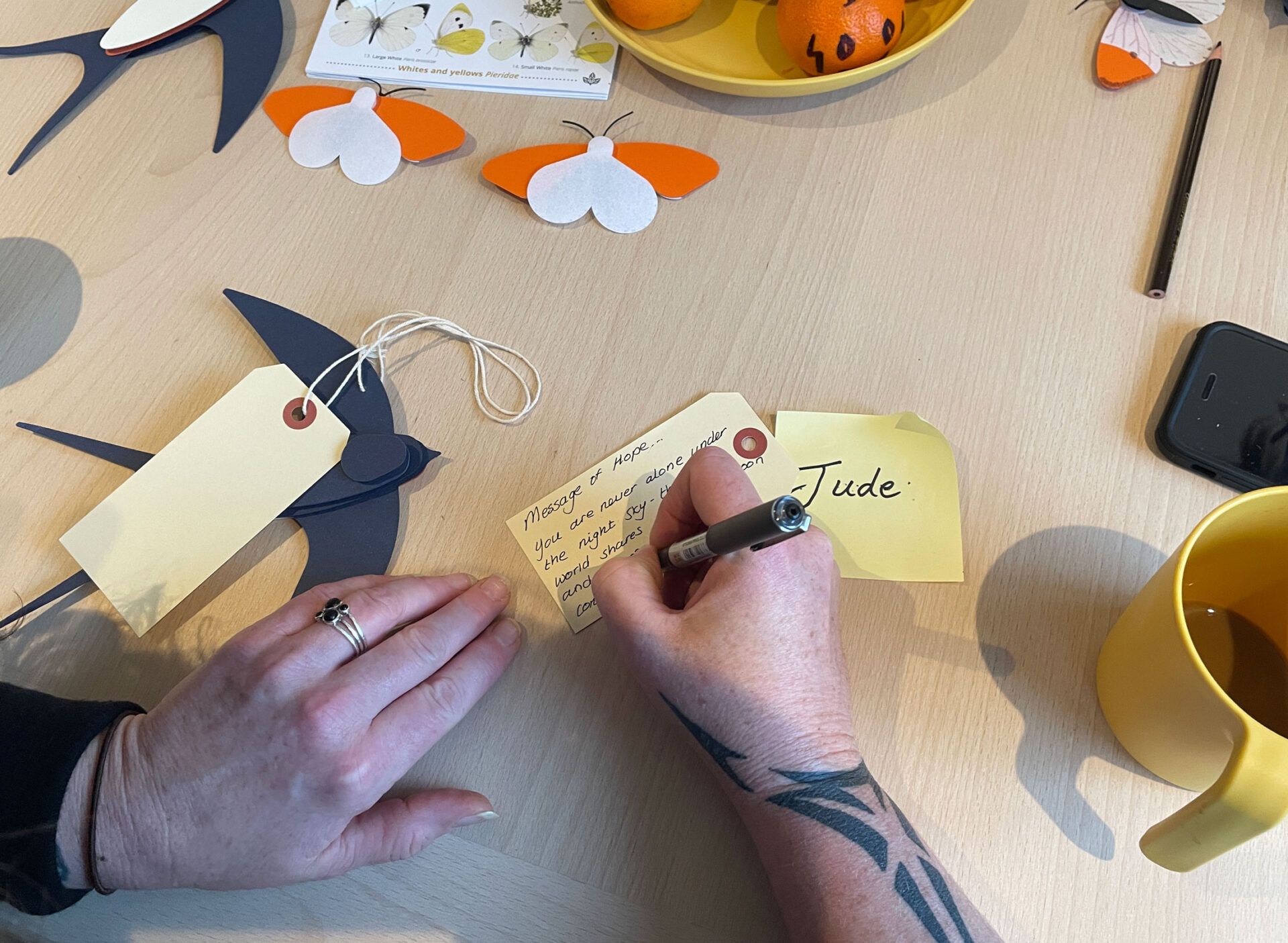 A close up of a hand writing a Message of Hope on a luggage label.