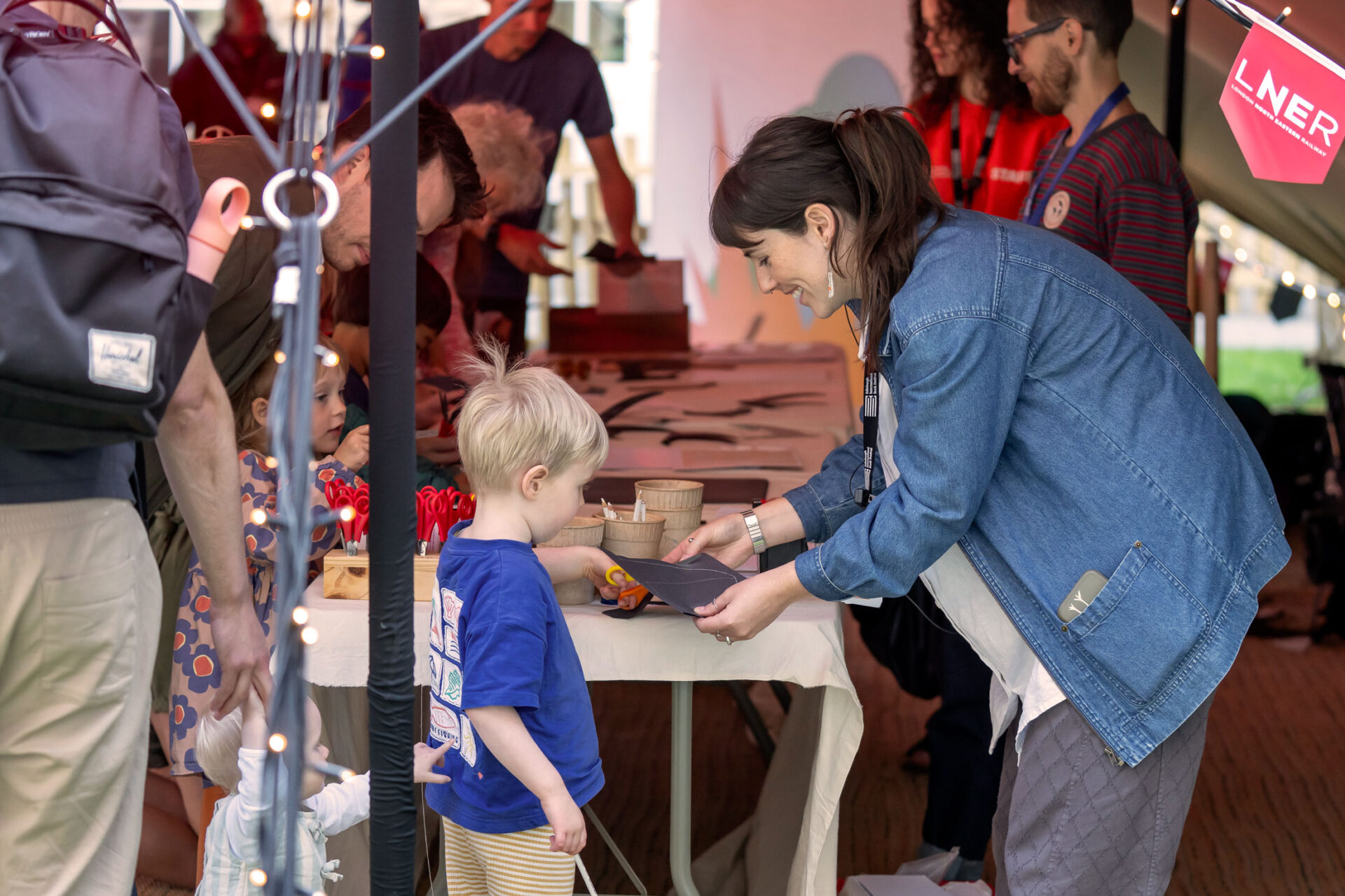 Young participant crafting a paper swift with an Edinburgh International Book Festival team member in the Family Tent.