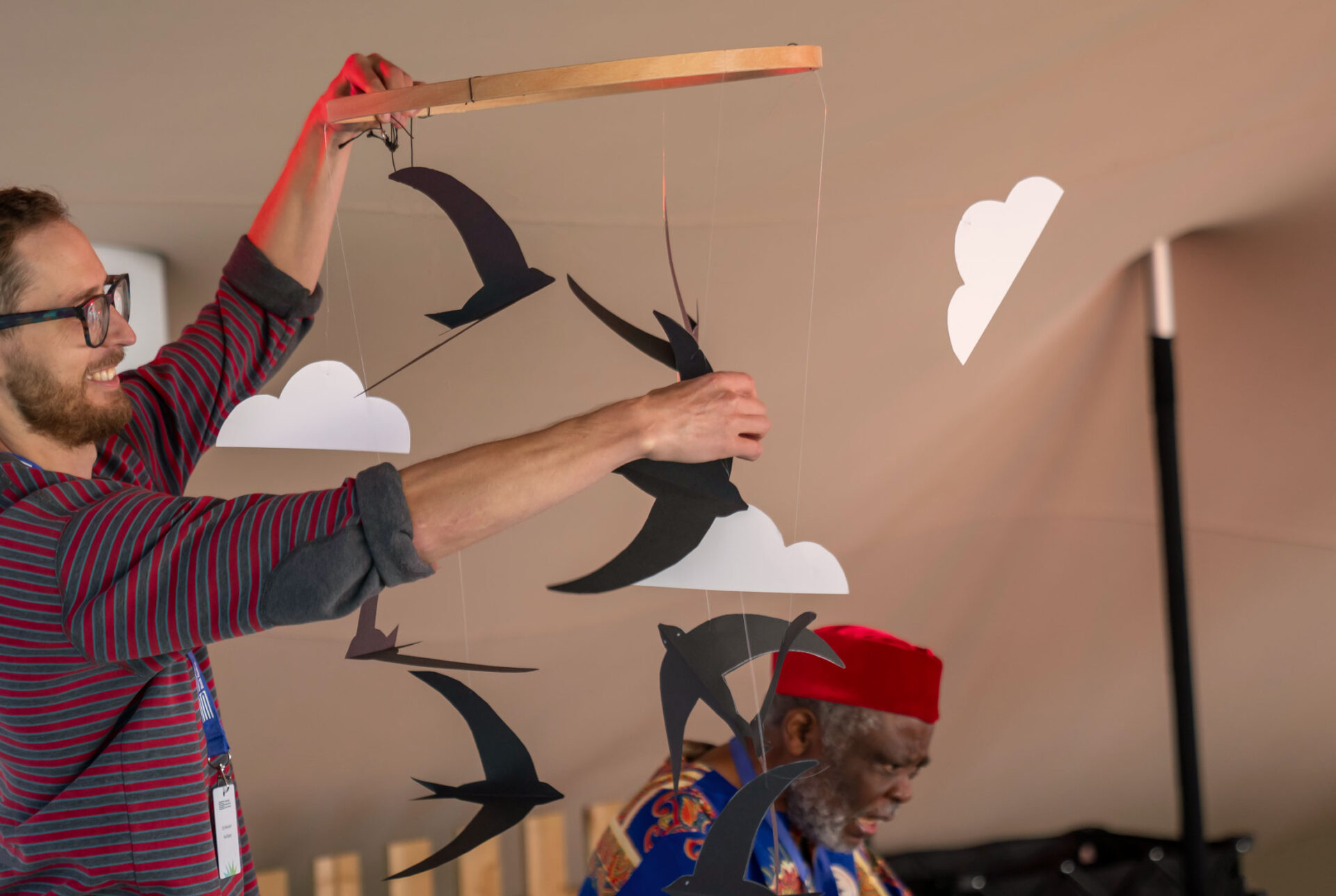 Welsh artist Ed Harrison holding up a community-created Mobile of Hope in the Children’s Tent at the Edinburgh International Book Festival.