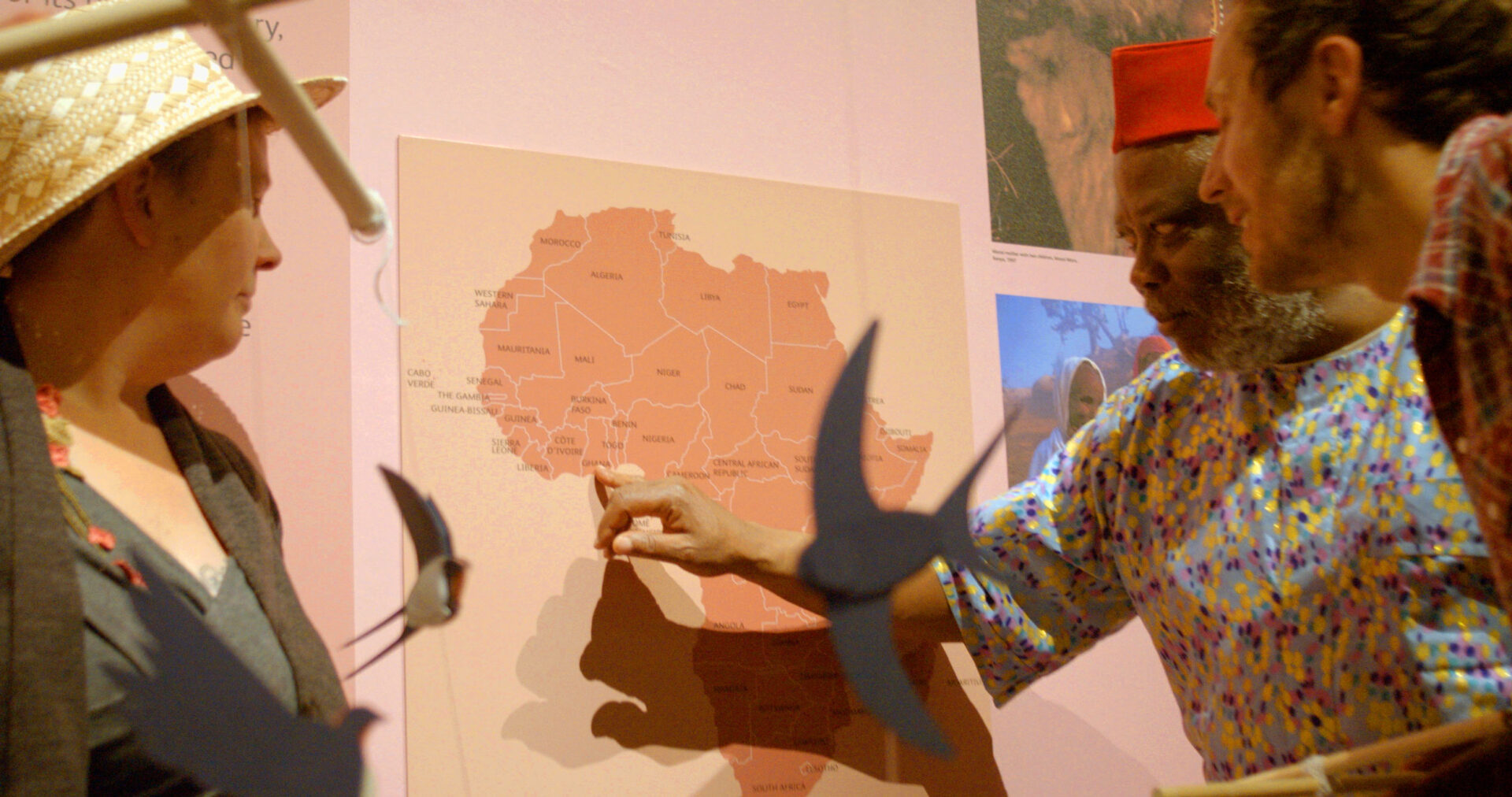 Ed Harrison, Chief Gift Amu-Logotse and Cara Silversmith discussing and pointing to a map of Africa.