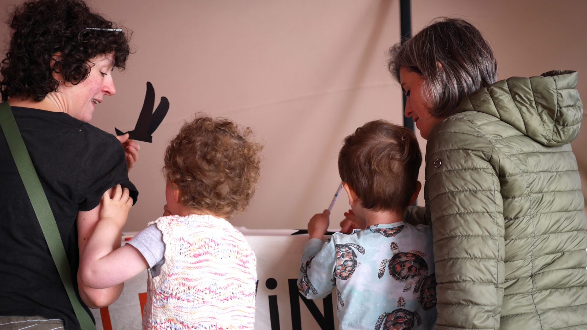 Two mothers overlook their two children making paper swifts at the Edinburgh International Book Festival.