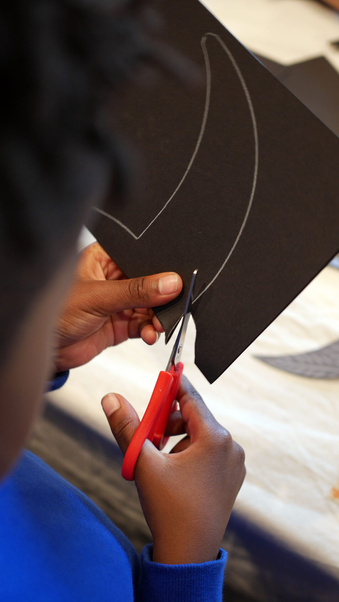 A child cutting a paper swift shape from black card.