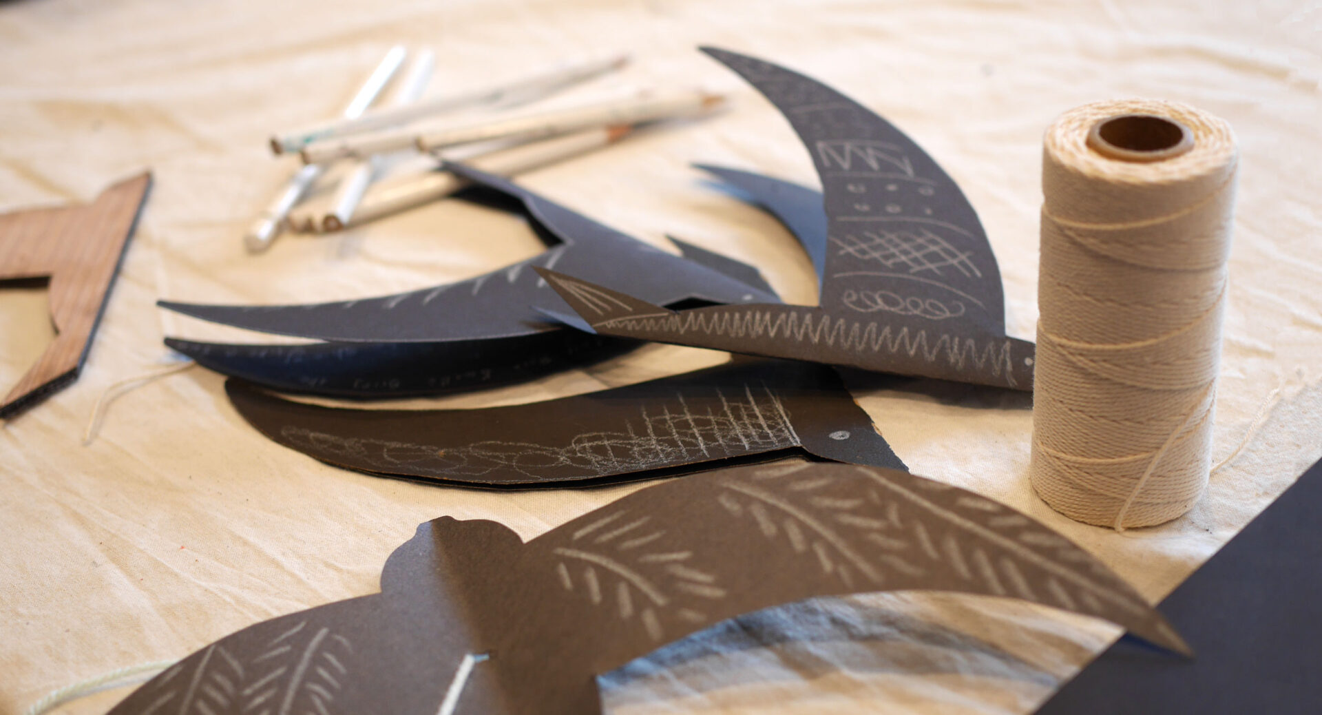 A pile of hand crafted paper swifts made from black card.