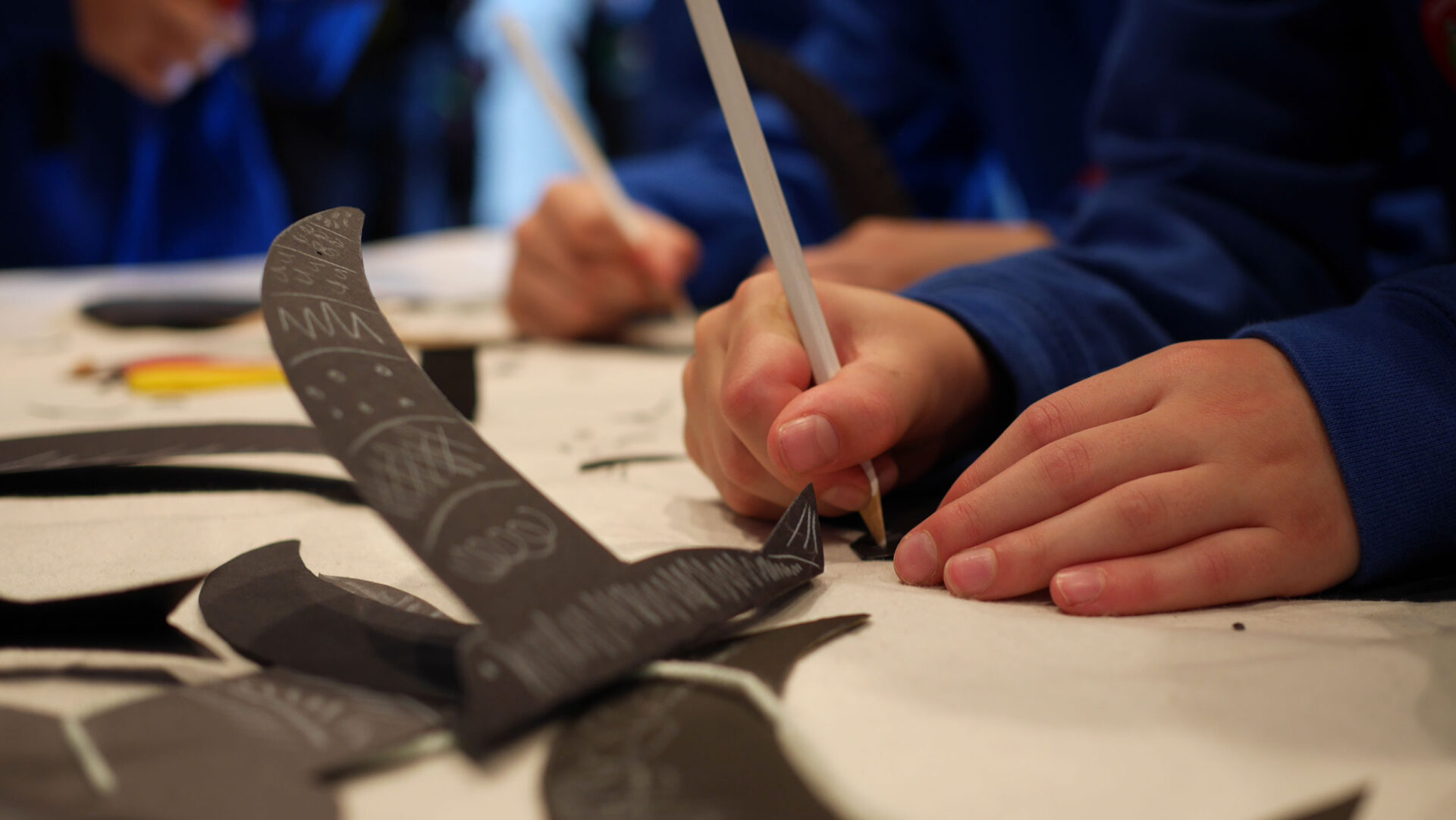 A child drawing eyes on a paper swift on black card.